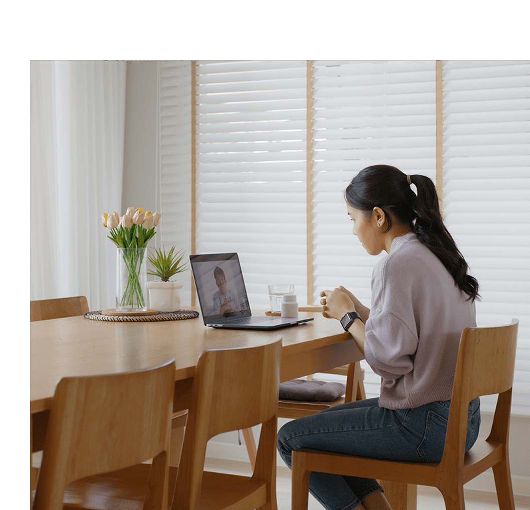 Woman working on a laptop in a bright, cozy dining area.