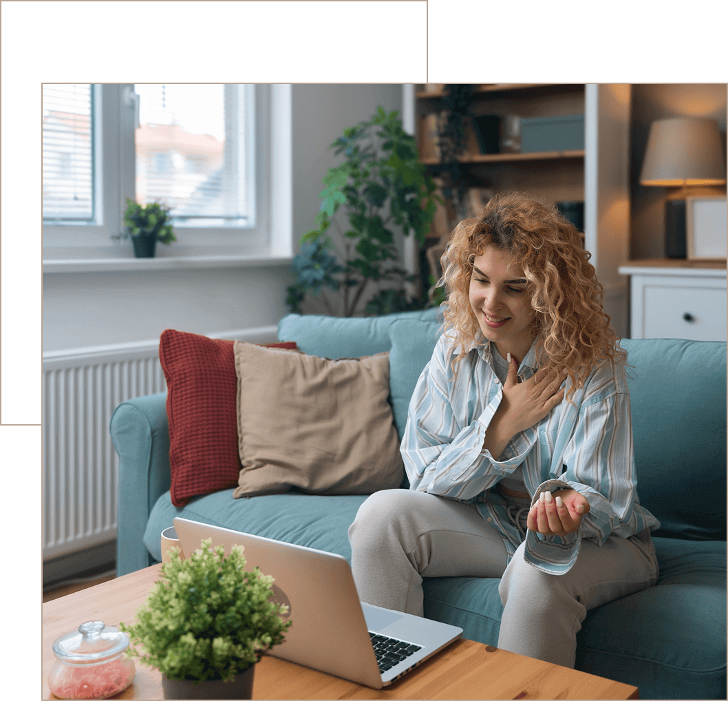 Woman happily video calling on her laptop from a cozy living room.