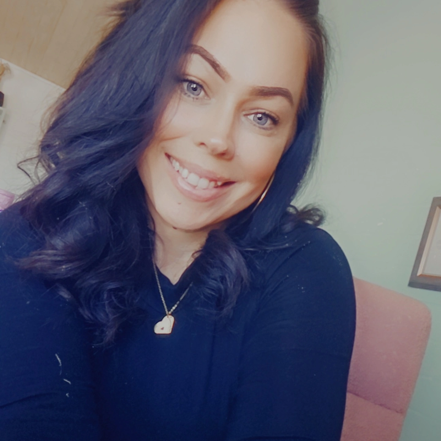 Smiling woman with dark hair indoors.