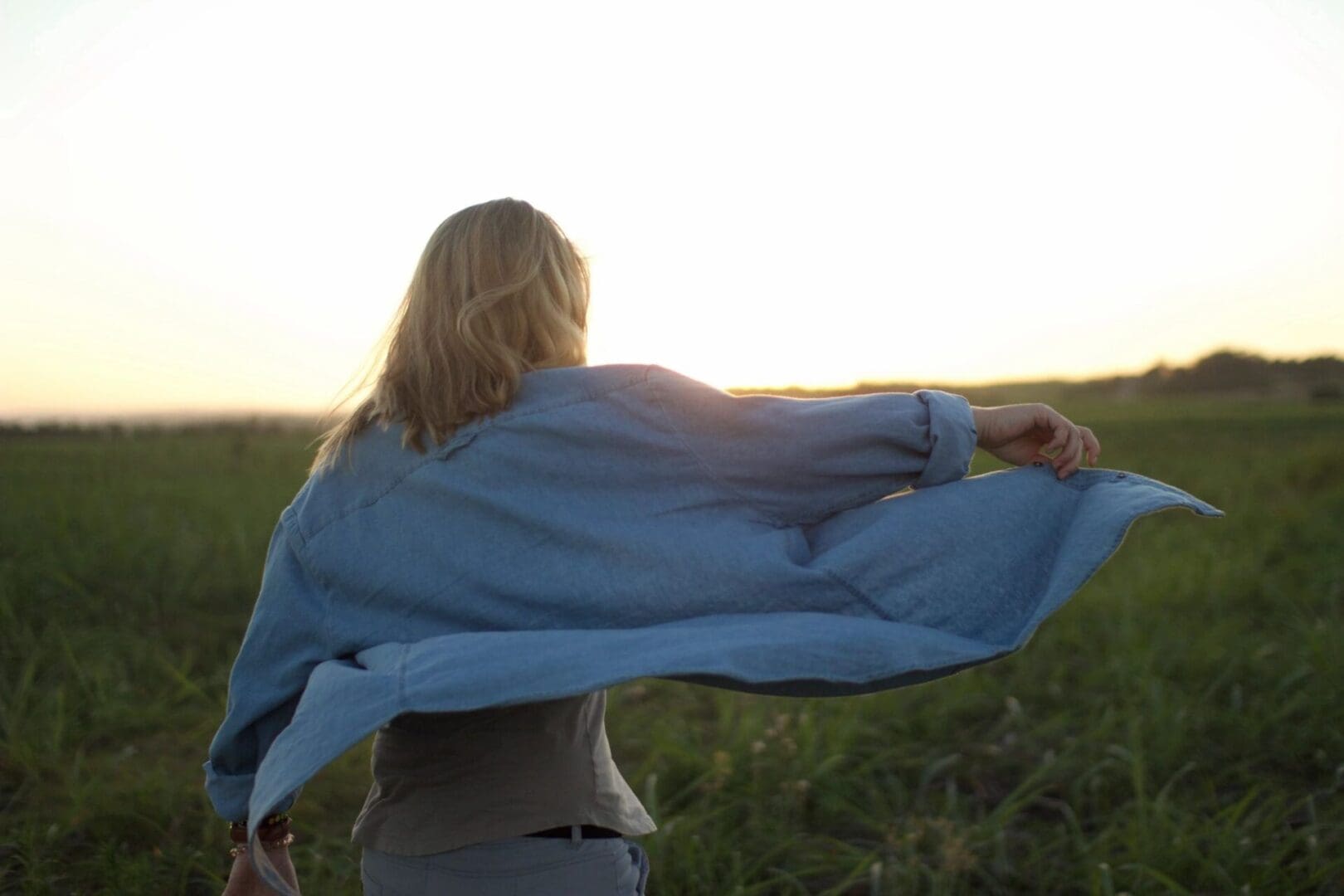 Woman in field with denim jacket.