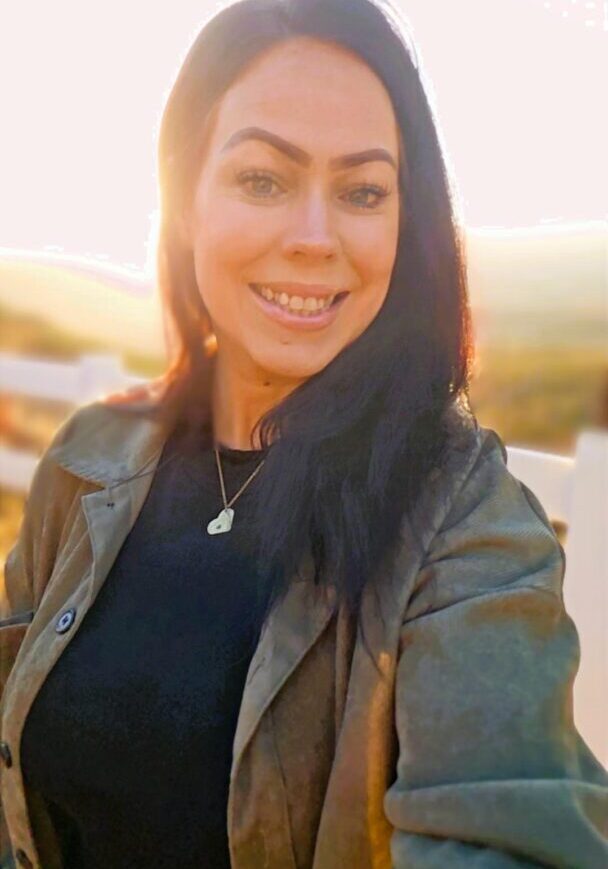 Woman smiling outdoors at sunset.